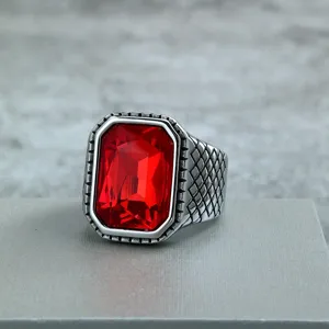 Detailed shot of a vintage stainless steel men ring with a faceted red glass stone and grid band.