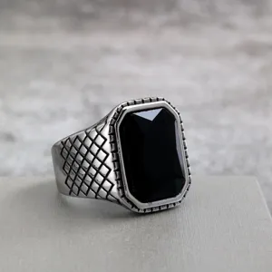 Closeup detail of retro stainless steel men ring with black faceted stone and lattice pattern.