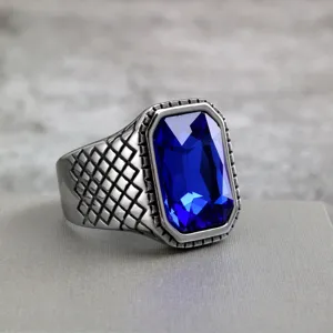 Close-up view of vintage stainless steel men's ring with large blue faceted stone and grid band.