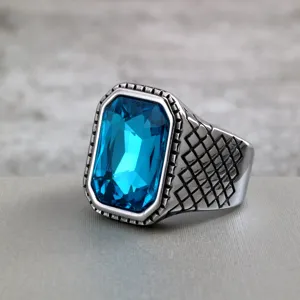 Close-up of vintage stainless steel men ring with faceted blue crystal and grid band.
