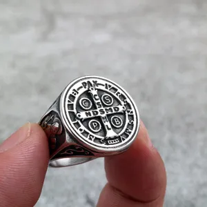 Close-up detail of the vintage stainless steel Saint Benedict cross ring worn on finger.