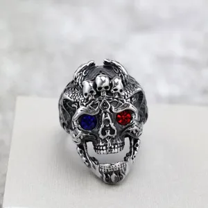 Detailopname van de stalen punk schedelring met gekerfde schubben en kristallen ogen.