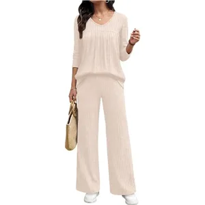 Detailed view of the pleated V-neck long sleeve top and wide-leg trousers set in soft beige.