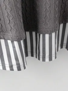 Primer plano de la textura de punto de chaleco gris sin mangas con dobladillo a rayas.