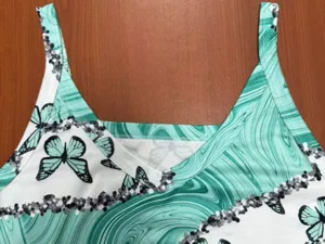Detailansicht eines ärmellosen Damen-Tops mit grünem Marmormuster und Schmetterlingsdruck.
