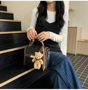 Close-up view of the vintage women handbag featuring plush bear pendant and metal lock hardware.