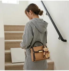 Detail view of a retro women's shoulder bag with cute bear charm and elegant brown leather finish.