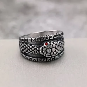 Close-up detail shot of retro stainless steel snake ring with red crystal eye and punk band.