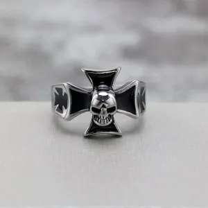 Detalle en primer plano de anillo para hombre de acero con cruz negra esmaltada y cráneo.