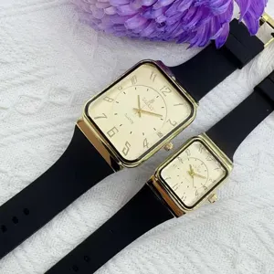 Orologio al quarzo di coppia con cassa rettangolare dorata e cinturino in silicone nero.