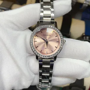 Détail de montre quartz femme DOUKOU avec cadran rose, lunette strass et bracelet en acier.