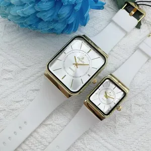 Detailaufnahme der Paaruhr mit weißem Silikonarmband und goldenem Zifferblatt.