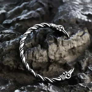 Primer plano detallado de brazalete nordico de acero inoxidable con cuervo y diseno trenzado.