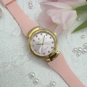 Detailed shot of women's quartz watch with pink silicone strap, gold case and rhinestones.