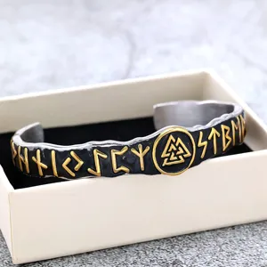 Gros plan sur le bracelet manchette runique viking en acier inoxydable aux symboles dorés.