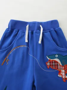 Boys blue summer shorts featuring cute shark and fishing rod embroidery with elastic waist.