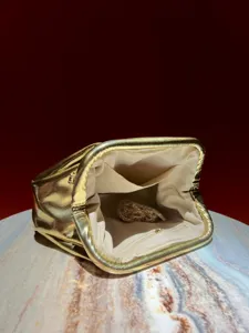 Detail view of a glamorous metallic gold evening clutch bag with metal frame, chain and lining.
