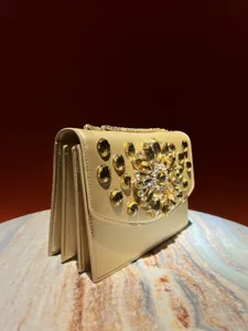 Gros plan détaillé du sac de soirée beige avec des ornements floraux en strass étincelants.