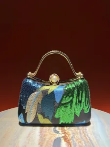 Detailed view of sequin embroidered evening clutch bag, delicate beadwork and metal handle.
