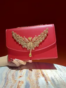 Elegante rote Abendtasche mit einem atemberaubenden goldenen Strass verzierten Flügelverschluss.