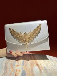 Exquisites Abend-Clutch-Taschen-Detail mit funkelnden Strasssteinen und goldenem Flügel-Design.