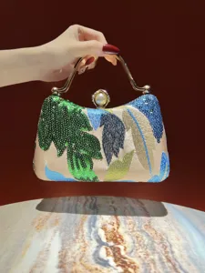 Detail view of the luxury sequin embroidered evening clutch with vintage metallic handle and pearl.