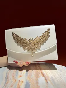 Elegante weiße Abendtasche Detail mit luxuriösem goldenem Kristall Schmetterlingsflügel.