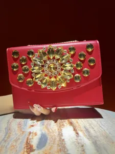 Gros plan du sac de soirée rouge avec de superbes grands détails de fleurs en cristal jaune vif.