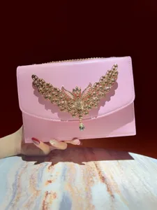 Detailansicht der luxuriösen rosa Abendtasche mit goldenem Strass Schmetterling Design.