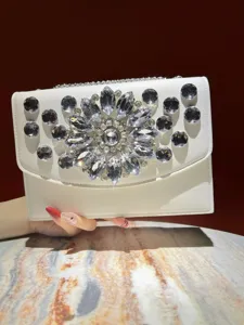 Détail de pochette de soirée blanche avec ornements floraux en strass cristal étincelants.