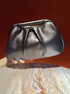 Detailed view of the black glossy pleated clutch handbag, featuring a stylish design.