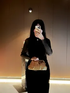 Gold metallic pleated clutch detail, elegant evening party bag worn in atmospheric scene.