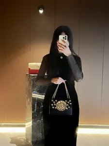 Élégante sacoche noire à chaîne avec des ornements floraux dorés et un design baroque luxueux.