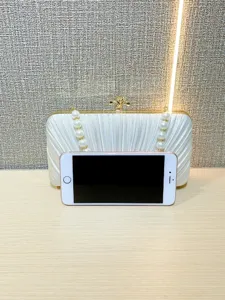 White pleated satin evening clutch bag with pearl chain and gold clasp for elegant parties.