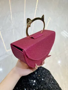 Sac de soirée rose à paillettes avec une élégante poignée métallique en forme de chat.