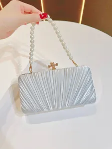 Silver pleated clutch bag detail with elegant pearl handle and metal clasp for evening dress.