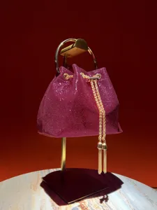 Sparkling purple bucket bag detail, featuring golden ring handle and chic chain tassels.