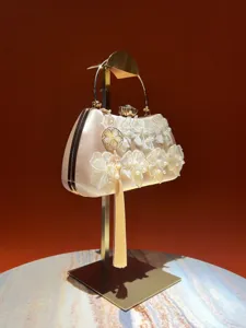 Exquisite evening clutch bag detail showing delicate floral lace appliques, pearls and elegant tassel.