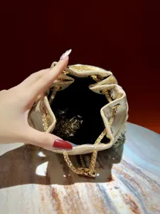 Gold glitter evening bucket bag detail showcasing luxury chain handle and plush interior.