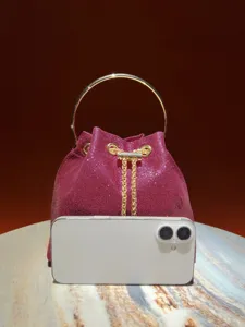 Sparkling bucket bag detail featuring metallic round top handle and fine chain drawstring.