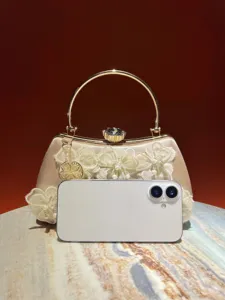 Detailed view of elegant evening handbag with floral lace and metallic round handle.