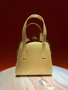 Detailed view of the elegant golden patent leather evening handbag with metallic frame and clasp.