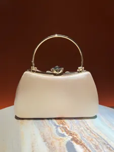 Elegant evening clutch bag detail showing smooth satin finish and vintage golden handle.