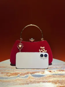 Dettaglio di una borsa da sera in velluto rosso con manico ad anello dorato e perle.