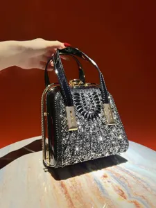 Detailed view of black rhinestone evening handbag, sparkling crystal details on hard shell.