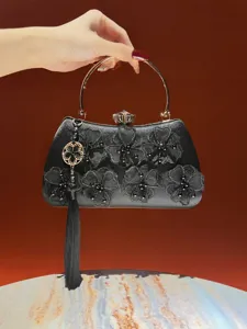 Elegant black evening bag with floral lace, metallic round handle, and chic tassel pendant.