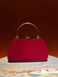 Vista dettagliata della borsa da sera elegante in velluto rosso con manico tondo dorato.