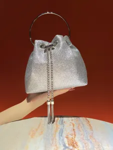 Silver glitter bucket bag with metal ring handle and chain tassels for evening parties.