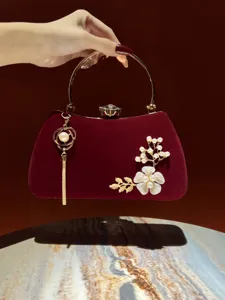 Elegante borsa da sera in velluto rosso scuro con manico rotondo, perle e nappe dorate.
