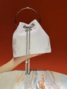 Shiny white bucket bag detail showing metal ring handle and chic chain tassels for evening events.